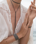 Load image into Gallery viewer, Close up of a model wearing a woven ruthenium finished sterling silver choker and long drop necklace with gold accents, styled with a wide cuff bracelet and slim band bracelet.