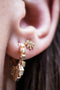 Load image into Gallery viewer, Model wearing 14k light yellow gold stud earrings featuring a sunburst design with an eye motif at the center, set with a diamond and accented by small gold dot details along the rays.