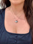 Load image into Gallery viewer, Model wearing sterling silver heart locket pendant by Anzie featuring a white sapphire gemstone and classic keepsake design.
