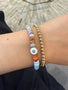 Load image into Gallery viewer, Anzie multicolored opal rondelle bead bracelet featuring a rhodium-plated sterling silver charm with white enamel and sparkling clear topaz accents stacked with gold beaded bracelet. 
