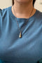 Load image into Gallery viewer, Model wearing sterling silver and brass sounding weight necklace with engraved waves and a two-masted schooner.
