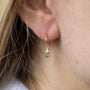 Load image into Gallery viewer, Model wearing 14k yellow gold earring featuring a deep blue tourmaline accented by three white diamonds. 
