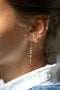 Load image into Gallery viewer, Model wearing 14k light yellow gold long earrings featuring a gradient of iridescent moonstones and white diamonds, accented with small gold sun and moon motifs for a celestial-inspired design with ear stack.
