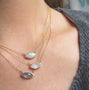 Load image into Gallery viewer, A close-up of a person wearing three layered 14K yellow gold necklaces one with moonstone  featuring a marquise rosecut moonstone.
