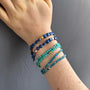 Load image into Gallery viewer, Model wearing turquoise bead bracelet with sterling silver accents by Philippa Roberts stacked with other bracelets.
