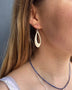 Load image into Gallery viewer, Model wearing sterling silver elongated oval drop earrings by Philippa Roberts, featuring a simple open hoop design.



