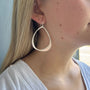 Load image into Gallery viewer, Close-up of a person wearing a silver large organic hoop earring against a neutral background

