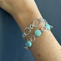 Load image into Gallery viewer, Model wearing a silver bracelet stacked with minimalist amazonite circle bracelet in sterling silver with blue-green gemstone links, 7.5 inch length, handmade in Oakland, California.
